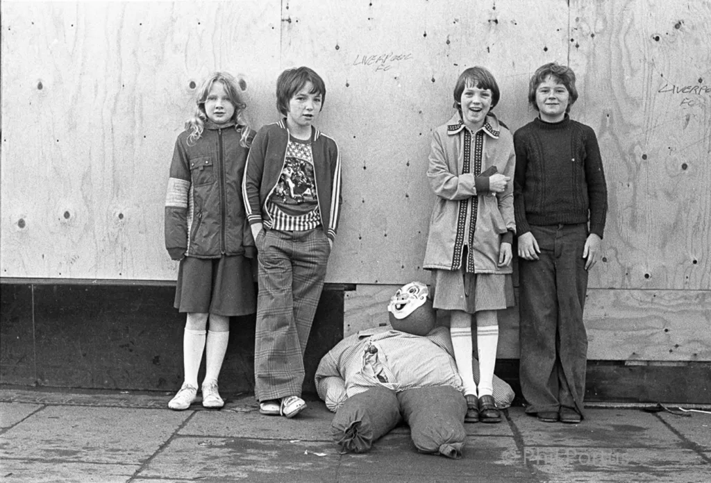 Five children stand near a fallen person in black and white.