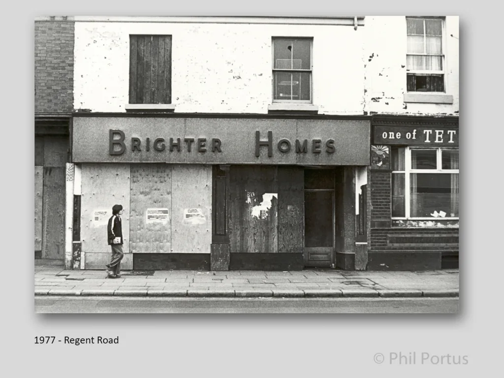 A black and white image shows a building with "Brighter Homes" signage above a doorway and a person walking past.