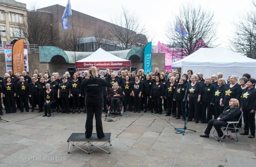 A large group of people wearing black clothing with gold accents gathers outdoors for an event.
