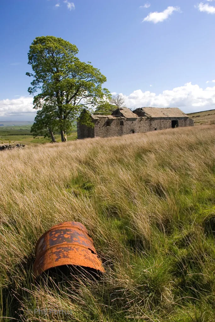 Derelict Lancashire Pennine farmhouse with a old rusty oil drum