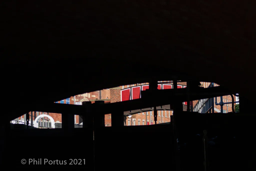 A dark silhouette of an arched bridge with visible windows and architectural details against a black sky.