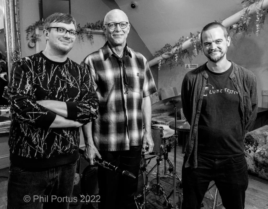 Three men stand together in a black and white portrait, smiling for the camera.