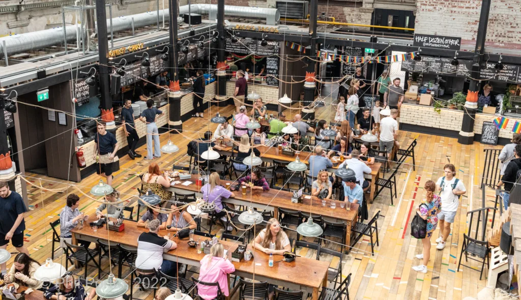 A large indoor space is filled with tables and chairs where many people are dining and socializing.