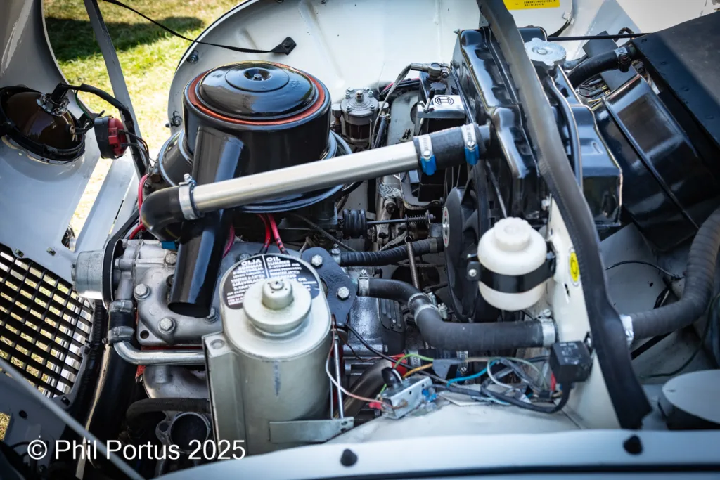 A vintage car engine compartment is visible with various components and hoses.